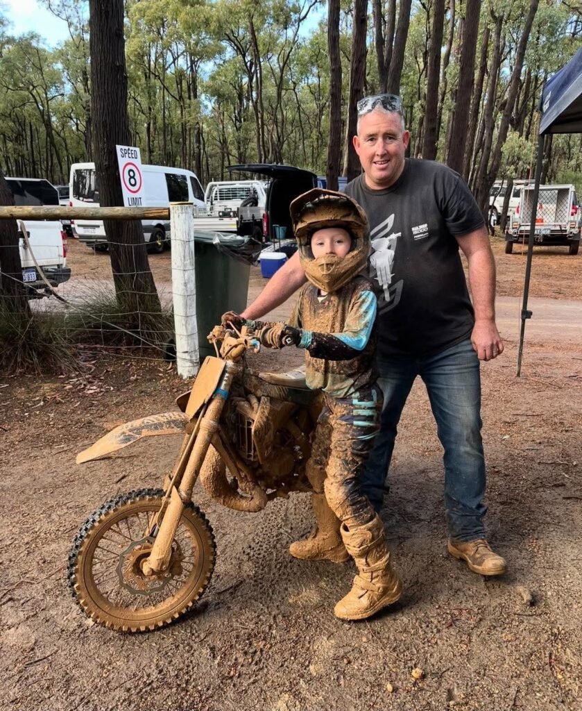 Evan Foley with his dad Wayne and his muddy motocross bike after a race